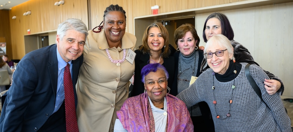 A gathering of friends smile at the camera.